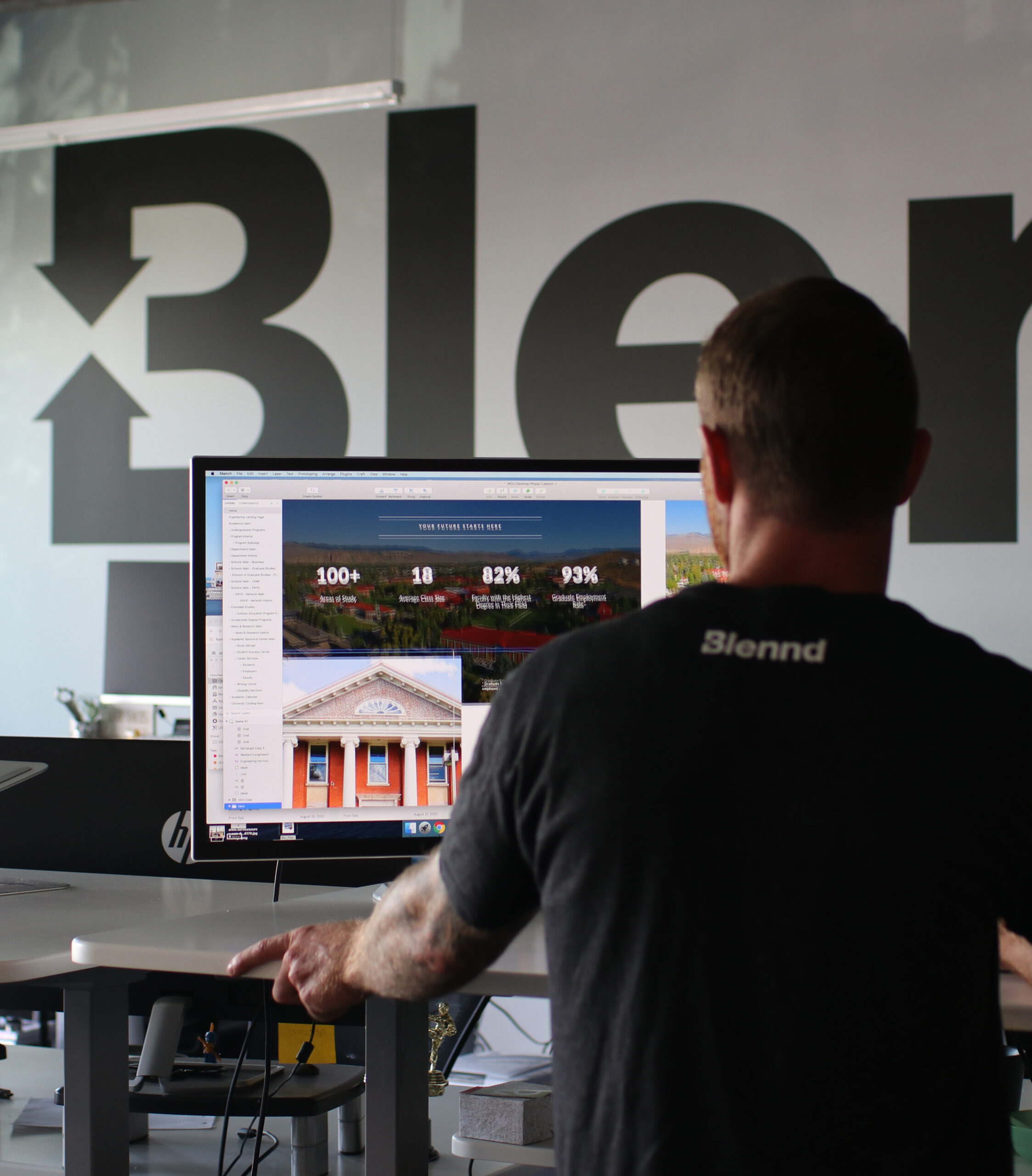 Designer reviewing website homepage on desktop monitor