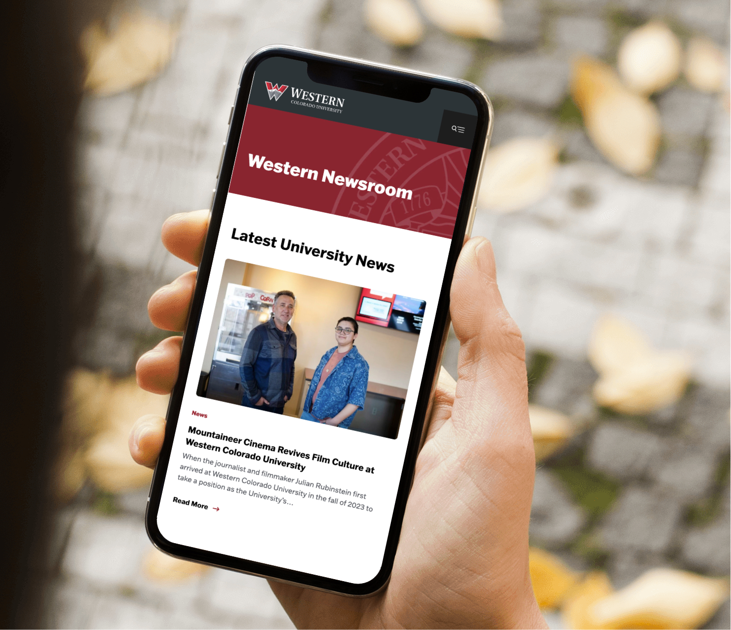Smartphone displaying university website in hand