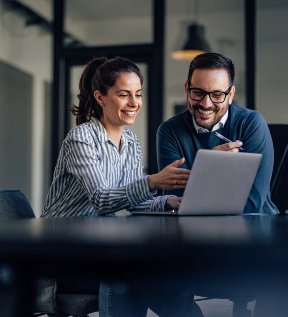 Two professionals collaborating on laptop in office