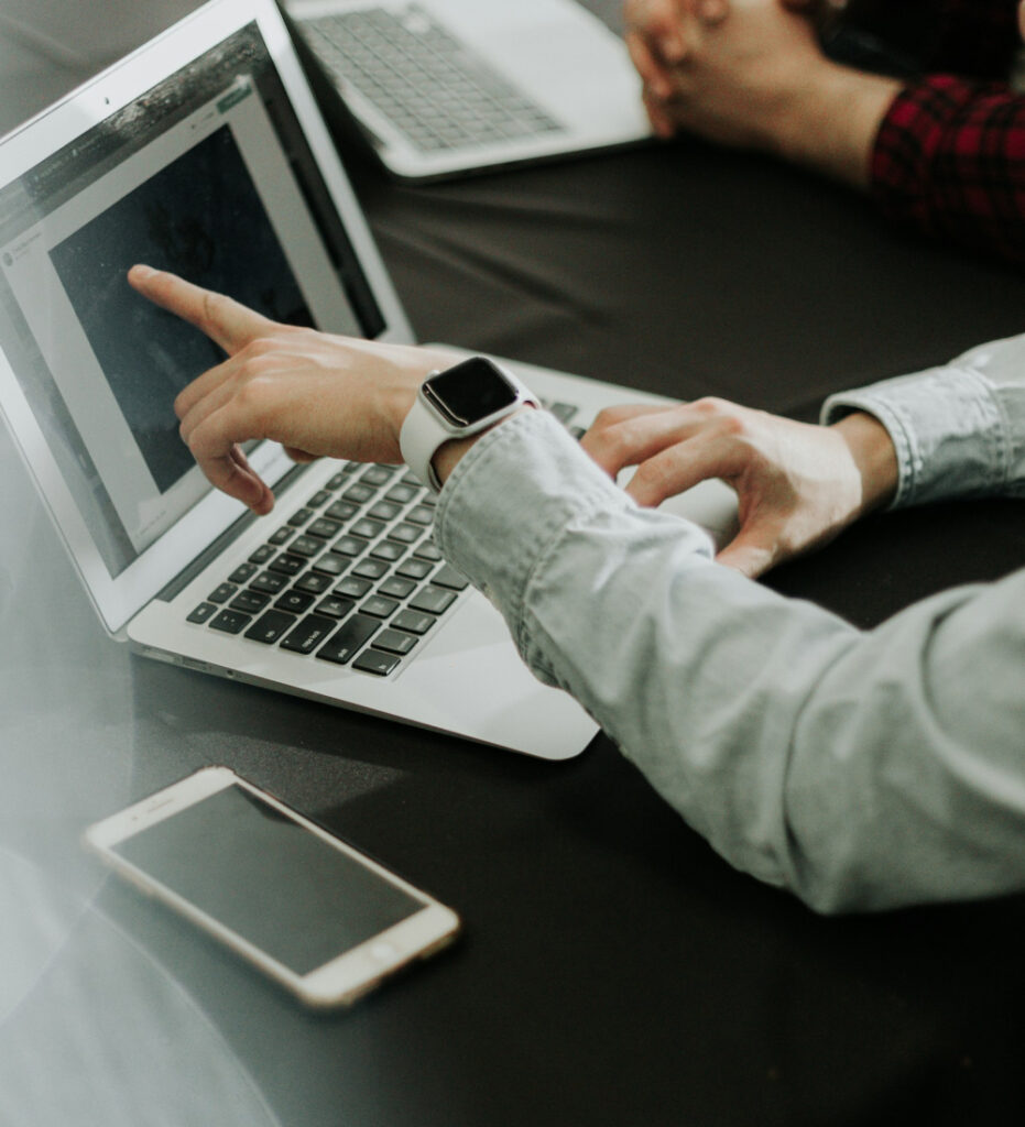 Person using laptop and pointing at screen